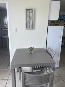 una mesa y sillas con un jarrón de flores. en Coast B&B - Agulhas, en Agulhas 13 fotos más