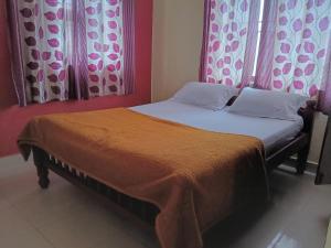 ein Bett mit zwei Kissen und einer orangefarbenen Decke in der Unterkunft Coorg homes & villas in Madikeri
