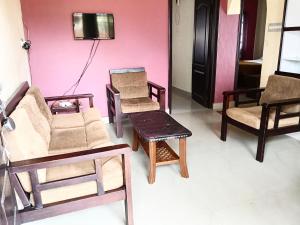 ein Zimmer mit Stühlen, einer Couch und einem Fernseher in der Unterkunft Coorg homes & villas in Madikeri