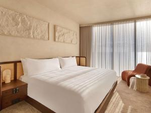 a bedroom with a large white bed and a chair at Mondrian Gold Coast in Gold Coast