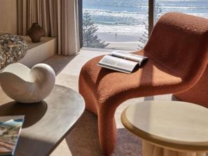 a living room with a chair with a book on it at Mondrian Gold Coast in Gold Coast