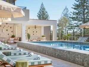 a pool with chaise lounge chairs next to a resort at Mondrian Gold Coast in Gold Coast