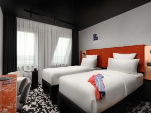 a hotel room with two beds and a chair at TRIBE Budapest Airport in Budapest