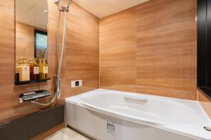 y baño con bañera y paredes de madera. en 難波站走路8分鐘包棟別墅 絕佳地理位置 最大16人, en Wada