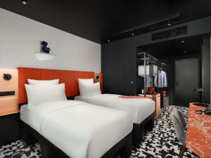 two beds in a room with white sheets at TRIBE Budapest Airport in Budapest