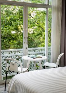 une chambre avec un lit et un balcon avec une table et des chaises dans l'établissement LeParc Hotel - Ben Thanh Market, à Hô-Chi-Minh-Ville