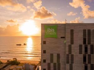 a building with a sign with the sun in the background at Ibis Styles Maragogi in Maragogi
