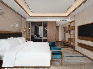 une chambre d'hôtel avec un lit et une télévision dans l'établissement Grand Mercure Kunming South, à Kunming