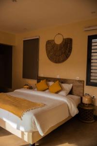 a bedroom with a large white bed with yellow pillows at Maison Inaya in Ngaring