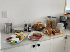 Un mostrador de cocina con platos de comida y pan. en Oceans Drift Guest House & Self Catering, en Simonʼs Town