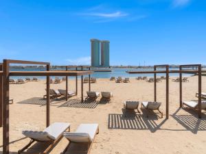 - une plage de sable avec des chaises longues et des chaises dans l'établissement Rixos Obhur Jeddah Resort & Villas - All-Inclusive, à Djeddah