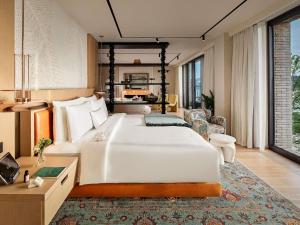 a bedroom with a large white bed and a living room at Aliée Istanbul - A Paris Society Collection Hotel in Istanbul