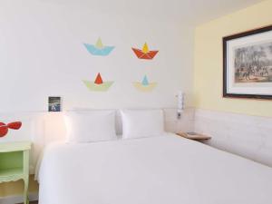 - une chambre dotée d'un lit blanc avec des étoiles sur le mur dans l'établissement Greet Hôtel Saint-Nazaire Trignac Nouvelle Marque du Groupe Accor, à Trignac