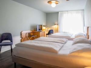 a room with three beds and a tv and a window at Mercure Hotel Pforzheim in Pforzheim