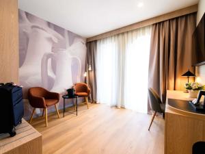 a living room with chairs and a tv in a room at Mercure Alba Iulia in Alba Iulia