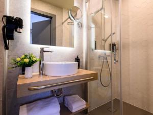 a bathroom with a sink and a shower at Mercure Alba Iulia in Alba Iulia