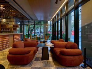 ein Restaurant mit orangefarbenen Stühlen und Tischen und Fenstern in der Unterkunft TRIBE Belo Horizonte Savassi in Belo Horizonte