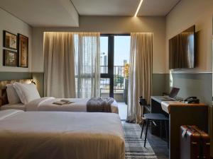 une chambre d'hôtel avec deux lits, un bureau et une fenêtre dans l'établissement TRIBE Belo Horizonte Savassi, à Belo Horizonte