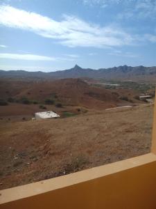 a view of a field with a barn and mountains at Ma maison de cha de marhina in Mindelo