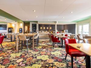 Un restaurante con mesas y sillas y una cocina. en ibis Styles Chartres Sud Barjouville, en Chartres