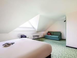 Un dormitorio con una cama y un sofá verde. en ibis Styles Chartres Sud Barjouville, en Chartres