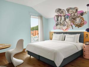 a bedroom with a large white bed and a painting on the wall at 25hours Hotel Sydney The Olympia in Sydney