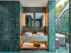 a bathroom with two sinks and a tub at 25hours Hotel Sydney The Olympia in Sydney