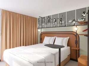 Un dormitorio con una cama blanca y una mesa. en ibis Styles Colombes Paris Ouest (Ouverture Octobre 2025), en Colombes