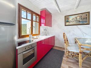 une cuisine avec des armoires rouges, une table et une fenêtre dans l'établissement Villa Kristina, Ermioni, à Plépi 9 autres photos