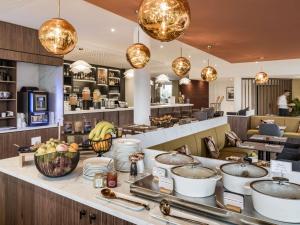a restaurant with bowls of food on a counter at Mercure Chartres Est in Chartres