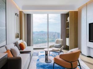 ein Wohnzimmer mit einem Sofa und Stühlen sowie einem großen Fenster in der Unterkunft Novotel Huzhou South Taihu Lake in Huzhou