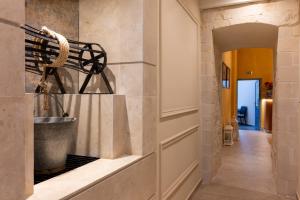 Un pasillo con una pared de piedra con un cubo en un estante. en Captain's House Hotel Suites & Apartments, en Panormos Rethymno