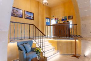 Una sala de estar con una escalera con una silla azul. en Captain's House Hotel Suites & Apartments, en Panormos Rethymno