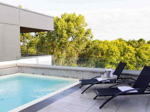une piscine avec des chaises et une table sur un balcon dans l'établissement ibis Styles Bordeaux Lac Bruges, à Bordeaux