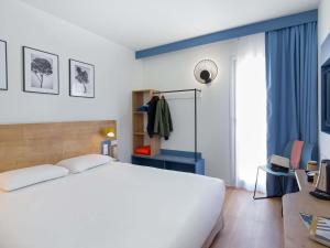 Un dormitorio con una cama blanca y una ventana. en ibis Styles Aubagne Gemenos, en Gémenos