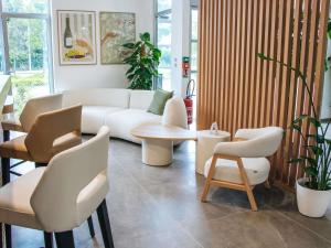 a living room with a couch and a table and chairs at Adagio Access Bordeaux Sud Pessac in Pessac