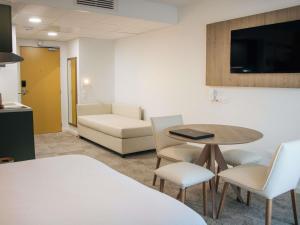 a living room with a table and chairs and a couch at Adagio Access Bordeaux Sud Pessac in Pessac