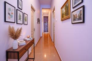 Un pasillo con paredes blancas y una mesa de madera y cuadros enmarcados. en Via Lishikaas Inn, en Tākalghāt