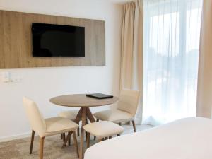 a room with a table and chairs and a tv at Adagio Access Bordeaux Sud Pessac in Pessac