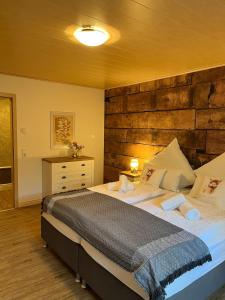 Rottal-AlpakaLodge Zeit zu Zweit im Grünen في Abtsgmünd: غرفة نوم بسرير كبير مع جدار خشبي