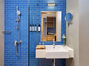 Mercure Phuket Patong Journeyhub في شاطيء باتونغ: حمام من البلاط الأزرق مع حوض ودش