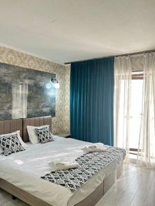 a bedroom with a large bed with blue curtains at The Artist Regency Hotel Tashkent in Toshkent-Passajir Bekati