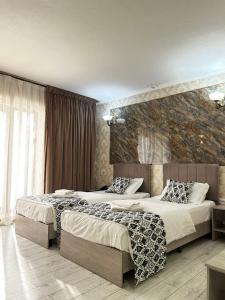 a bedroom with two beds and a stone wall at The Artist Regency Hotel Tashkent in Toshkent-Passajir Bekati