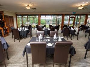 un comedor con mesas, sillas y ventanas en Clare Country Club, en Clare