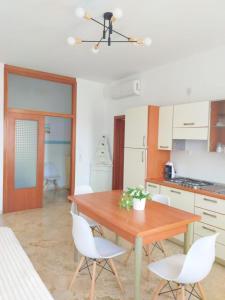 a kitchen with a wooden table and white chairs at Trilocale vacanza Riccione in Riccione