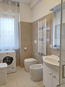 a bathroom with a washing machine and a toilet and a sink at Trilocale vacanza Riccione in Riccione +7 photos