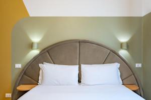 Bett mit einem Kopfteil aus Holz mit zwei weißen Kissen in der Unterkunft Hotel Infinito - Gruppo BLAM HOTELS in Rom + 58 Fotos