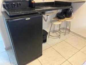 ナタールにあるPrático 228のカウンター横のキッチンにある黒い冷蔵庫