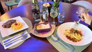 a wooden table with plates of food and glasses of wine at Kyriad Dijon Est Mirande in Dijon