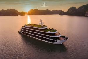 a cruise ship in the water at sunset at Venus Cruises Halong Bay by Venus Group in Ha Long